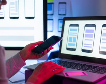 Designer projektuje UI telefonu na laptopie.